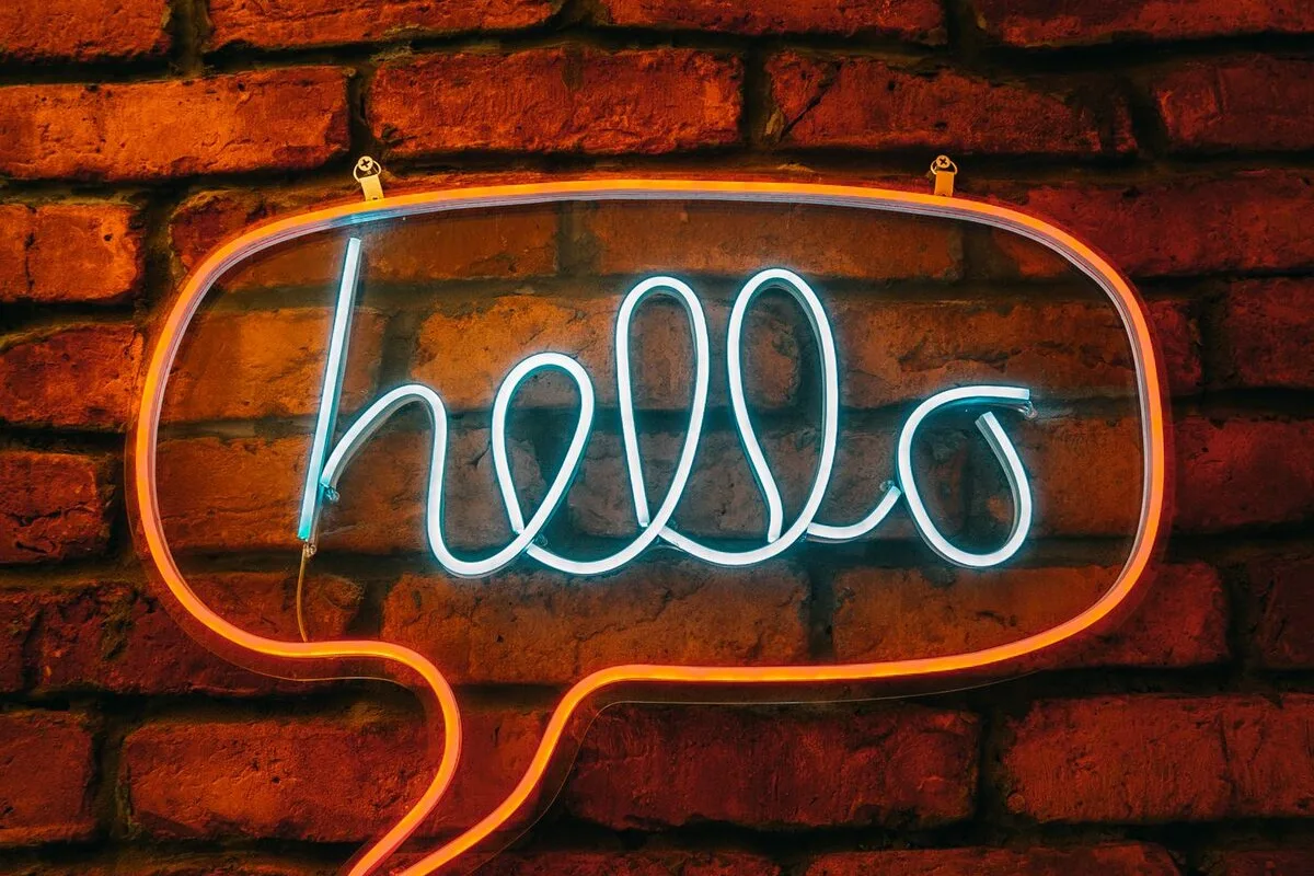Neonowy dymek dialogowy na ceglanej ścianie — Dobór narzędzi AI do obsługi czatu na stronie firmowej (chatbot)