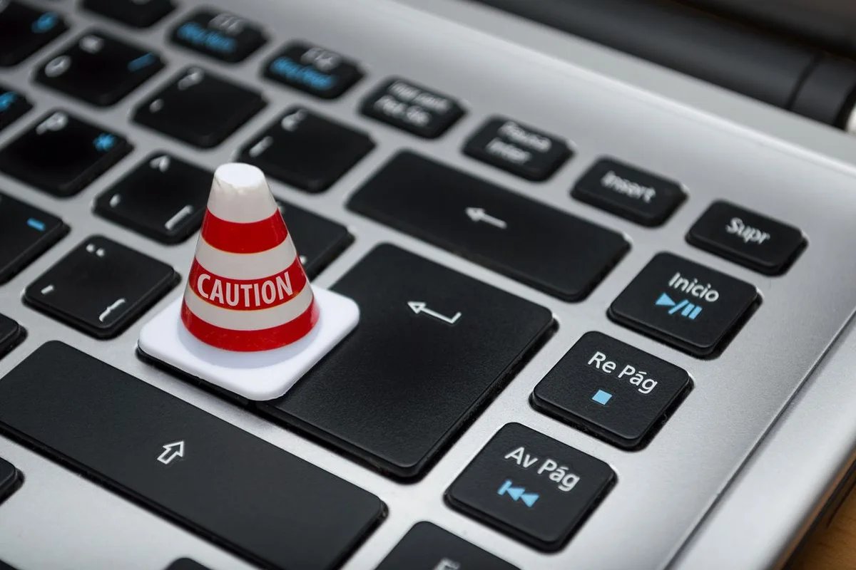 Pachołek z napisem CAUTION na klawiaturze laptopa — typowe błędy przy wdrożeniu