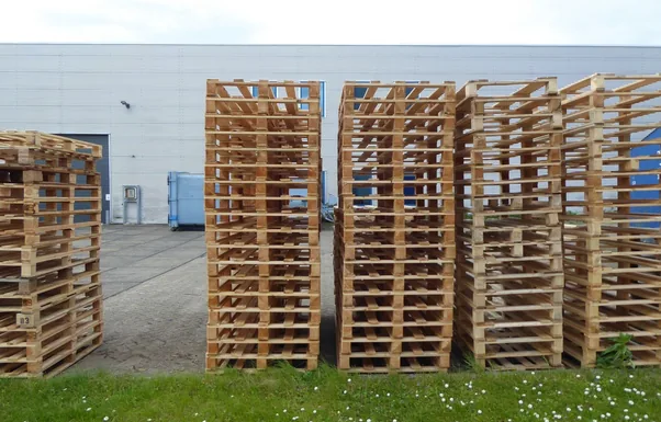 Rows of wooden pallets stacked outdoors near a warehouse, perfect for industrial and logistics themes.