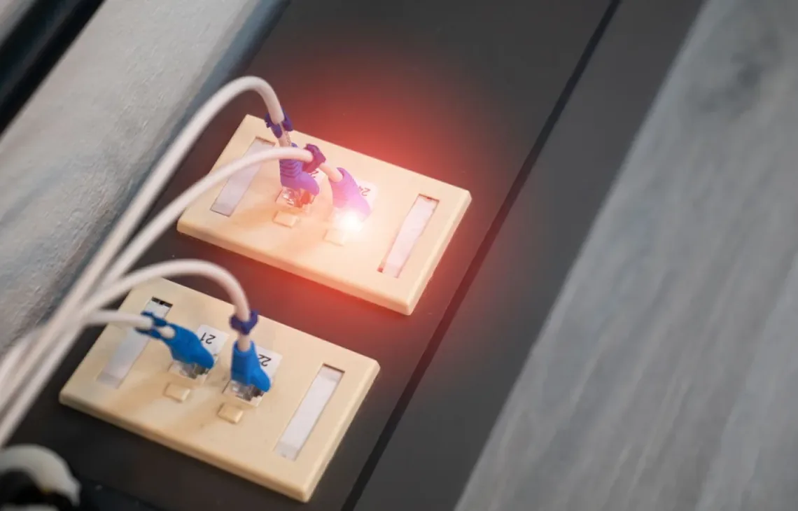 Gniazda sieciowe ścienne z podświetlonymi na czerwono wtyczkami