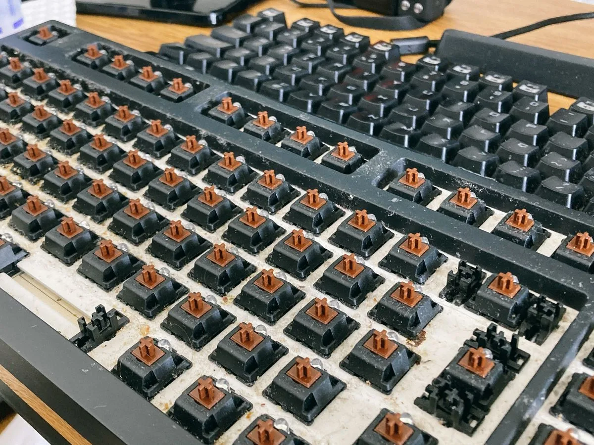 Zbliżenie mechanicznych przełączników klawiatury po zdjęciu klawiszy, widoczny pył — Specjalizujemy się w naprawach sprzętu narażonego na pył i zanieczyszczenia