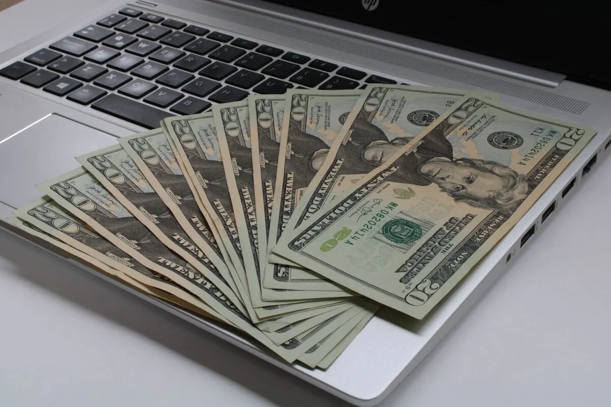 Banknoty dolarowe ułożone na klawiaturze laptopa HP — Zgłoszenie potrzeby zakupu i konfiguracji nowego komputera