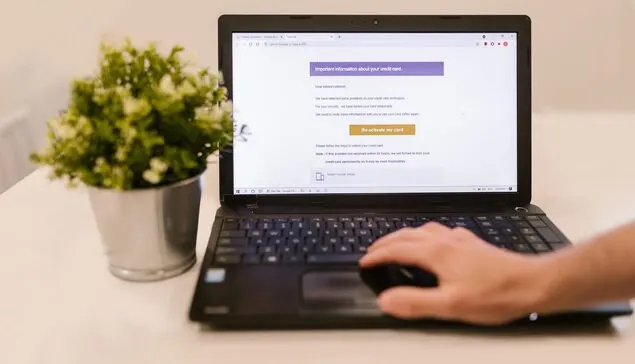 Dłoń na laptopie z ekranem podejrzanej wiadomości e-mail o karcie kredytowej — Konfiguracja szyfrowania i podpisu cyfrowego wiadomości e-mail