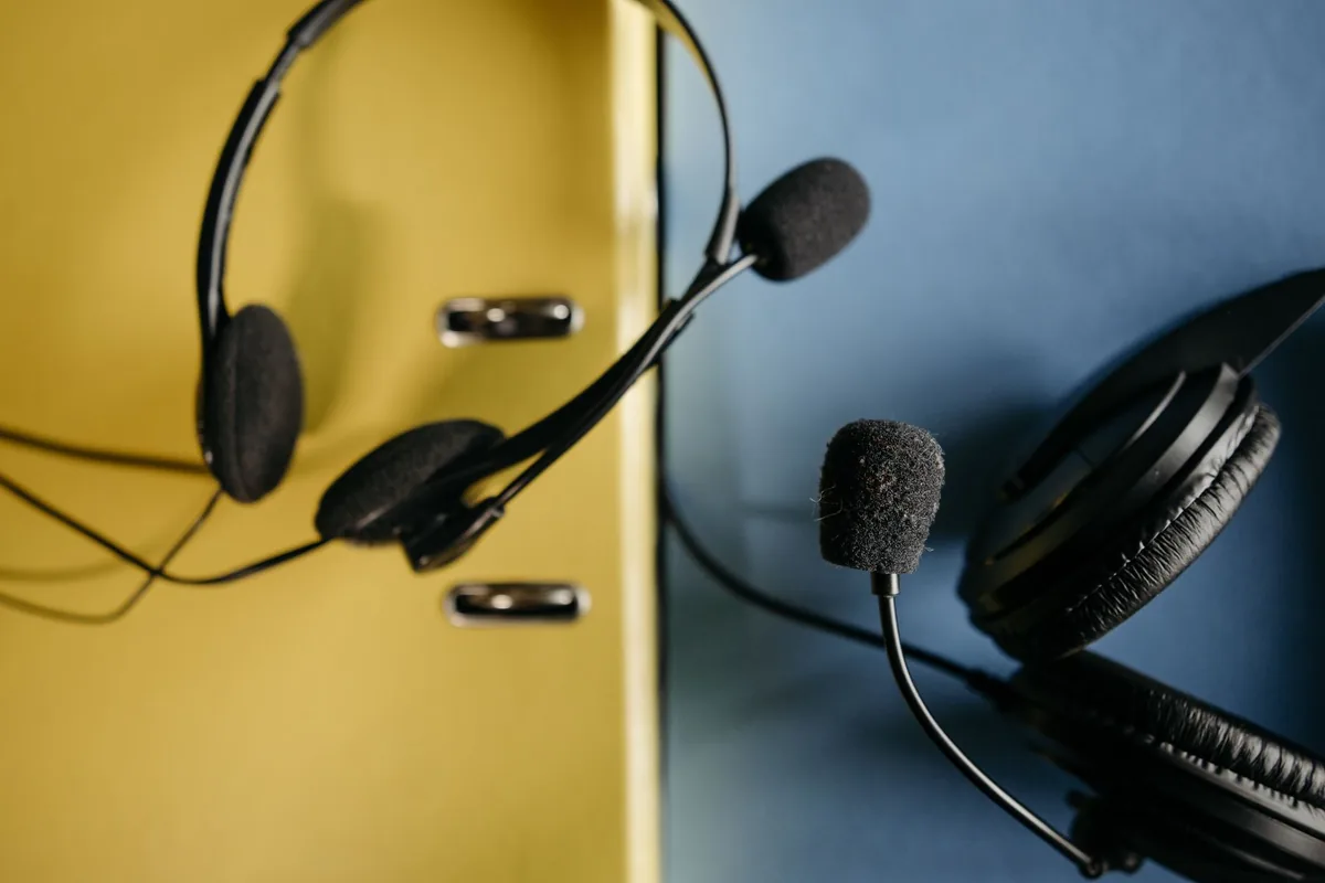 Close-up of headphones with attached microphones on a vibrant yellow and blue background, perfect for tech-related content.