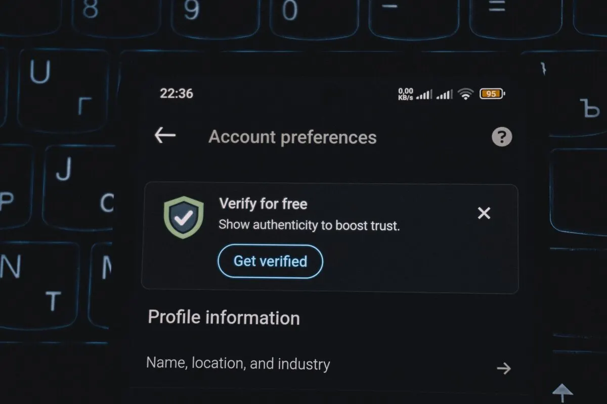 Ekran telefonu z ustawieniami konta i preferencjami profilu na tle klawiatury — Przenoszenie profilu i ustawień użytkownika na nowy laptop