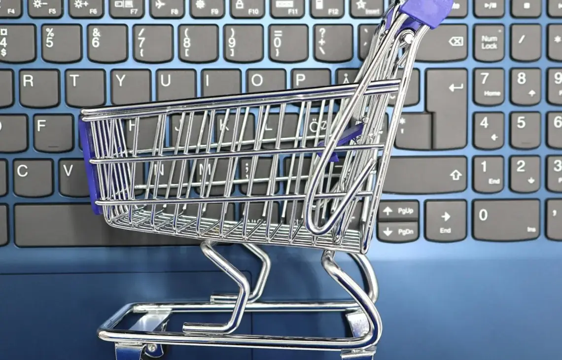 Miniaturowy wózek sklepowy stojący na klawiaturze laptopa — Dobór narzędzi AI wspierających dział zakupów
