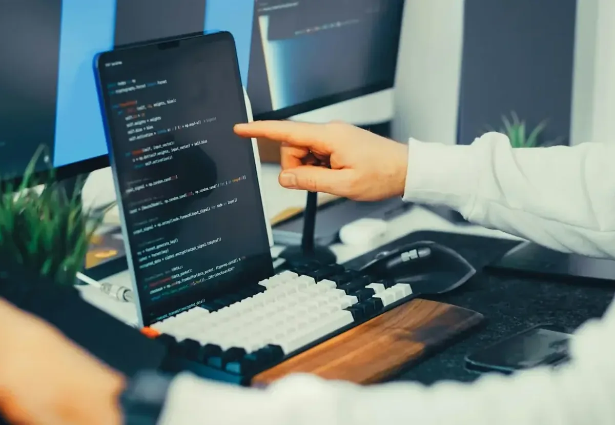 Dłoń wskazująca ekran z generycznym kodem programistycznym, brak związku z Wapro
