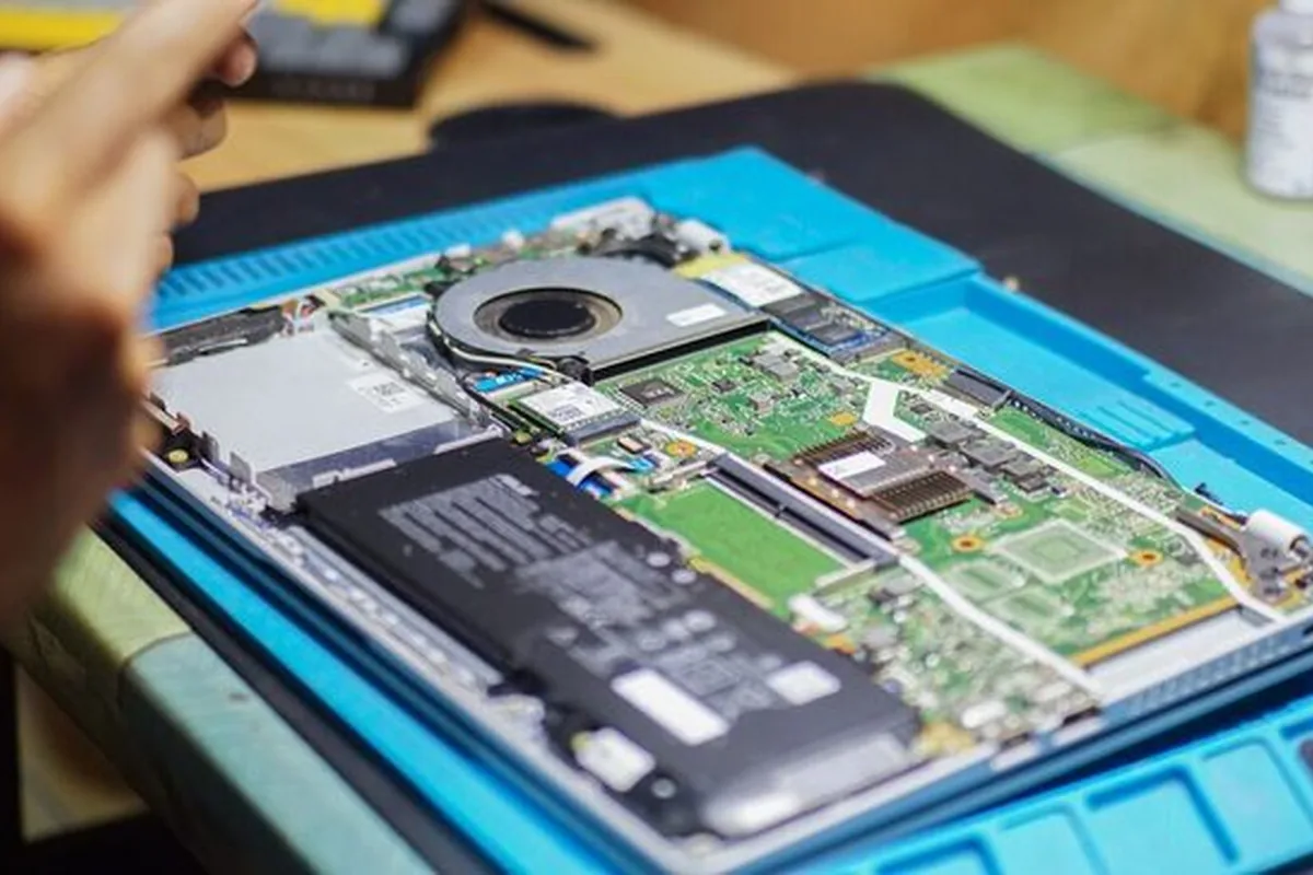 Otwarty laptop na macie serwisowej z widoczną płytą główną i baterią (bateria nie jest widocznie spuchnięta)