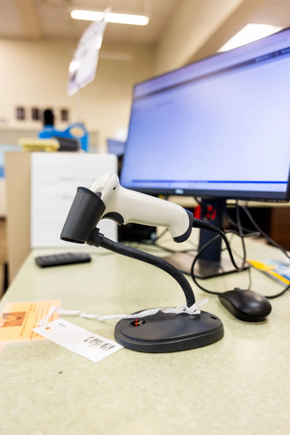 Skaner kodów kreskowych na stojaku przy monitorze komputera na kontuarze sklepowym — Integracja sklepu z WF-Mag i Comarch ERP Optima