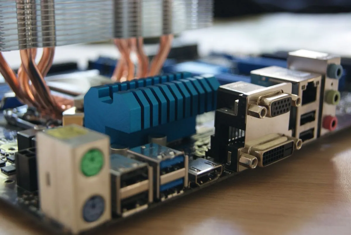 Zbliżenie na tylny panel komputera z portami I/O płyty głównej, widoczne gniazdo sieciowe — Wymiana kondensatorów i cewek uszkodzonych po przepięciu