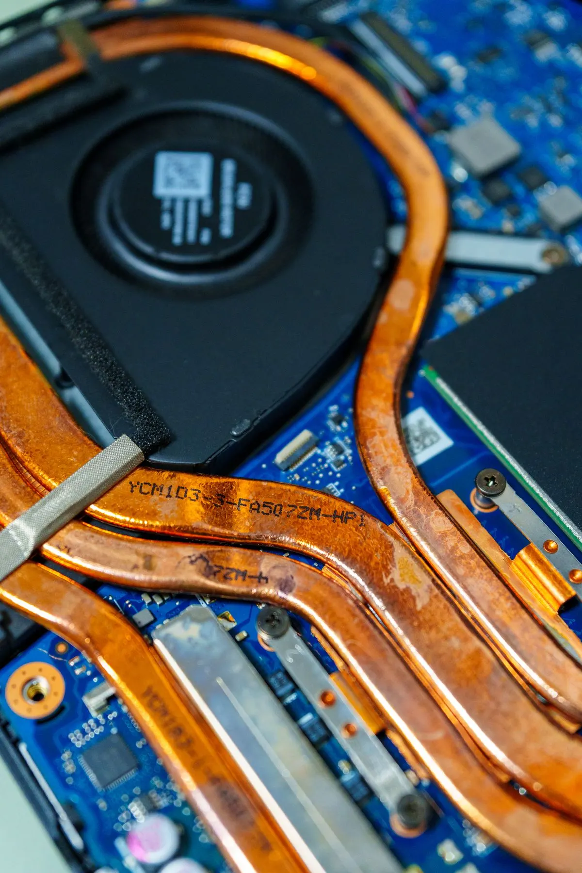 Wnętrze laptopa — wentylator chłodzący i miedziane rurki cieplne, zbliżenie — Radiator i rurki cieplne (heat pipes) jako podzespół laptopa