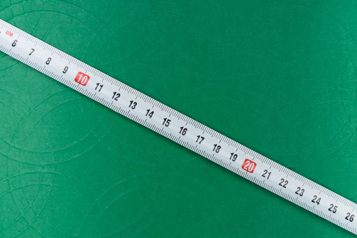 A close-up shot of a tape measure on a textured green background, showing precise measurements.