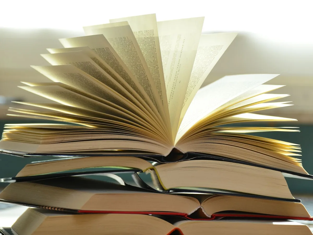 A close-up of a stack of open books with pages fanned out, capturing a study atmosphere.