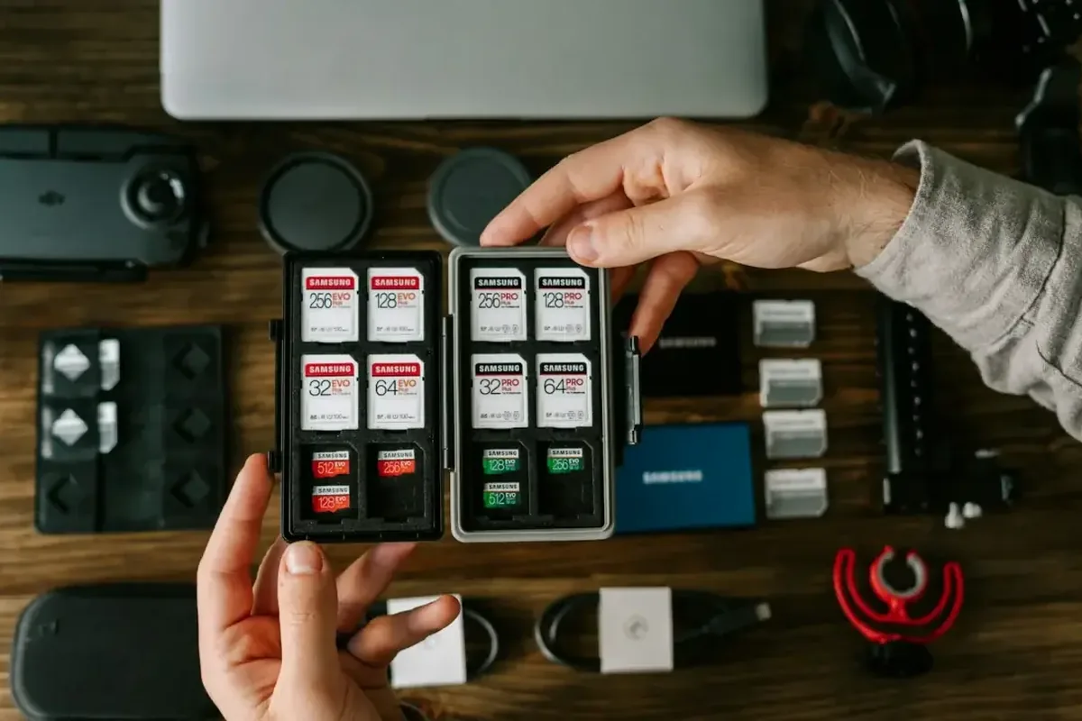 Dłonie trzymające etui z kartami pamięci Samsung obok dysku SSD