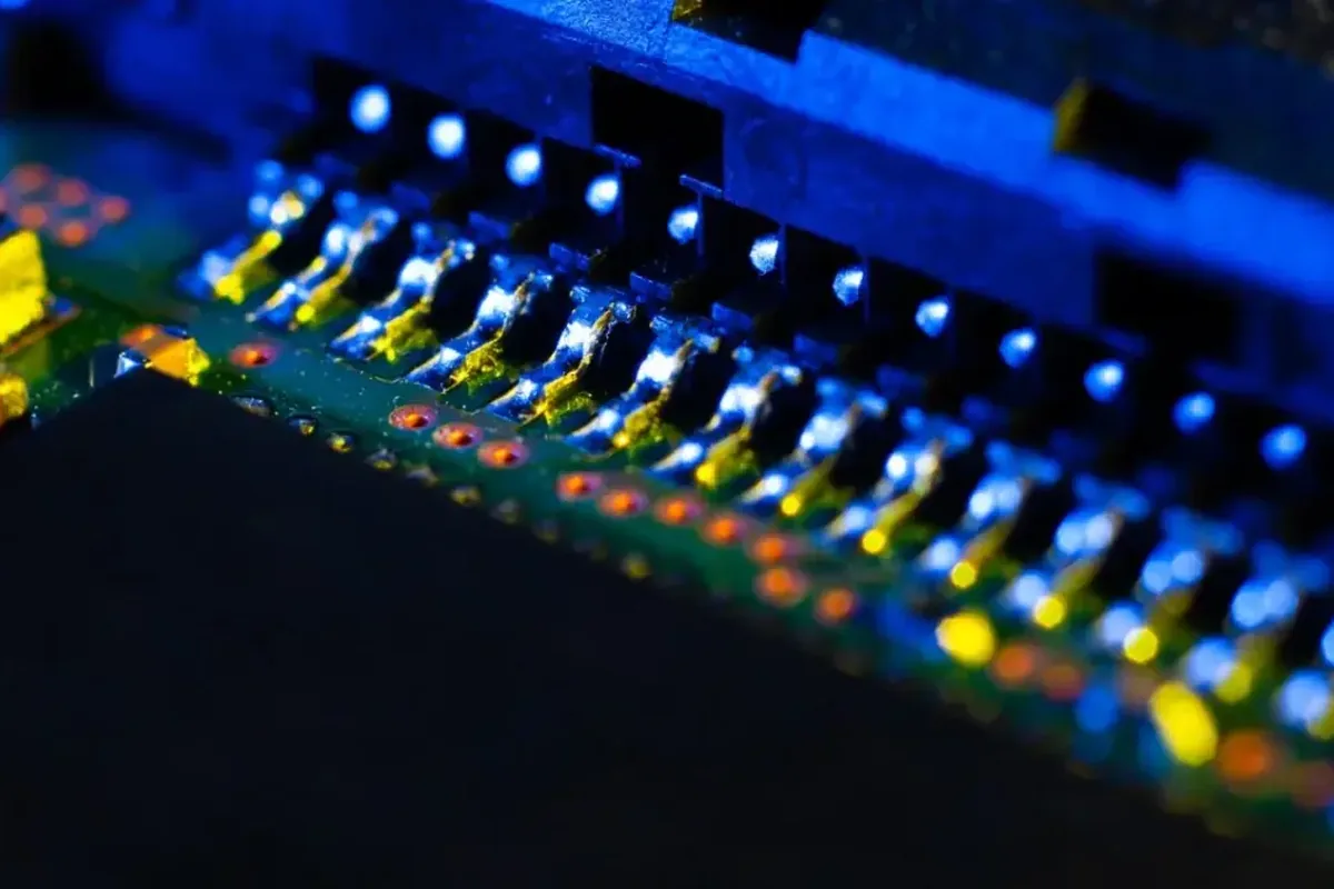 Makrofotografia podświetlonych na niebiesko pinów i złączy na płycie PCB, bez widocznych dłoni ani lutowania