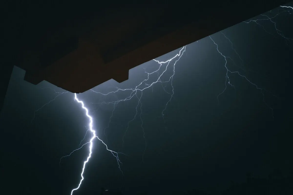 Wyładowanie atmosferyczne nad miastem symbolizujące przepięcie — Awaria UPS-a i utrata zasilania awaryjnego w serwerowni