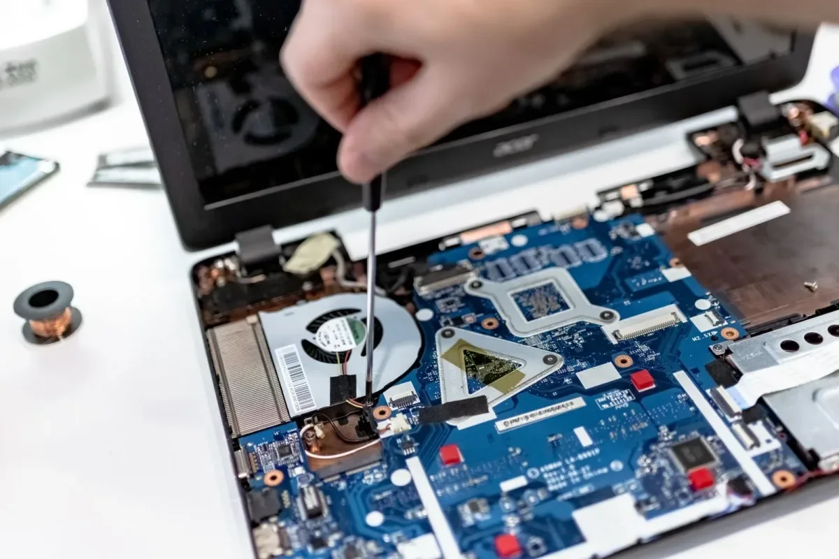 Serwisant odkręcający śrubę w otwartym laptopie