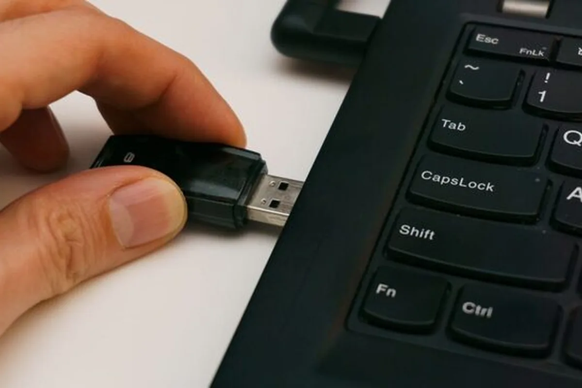 Dłoń wkładająca pendrive do portu USB laptopa typu ThinkPad
