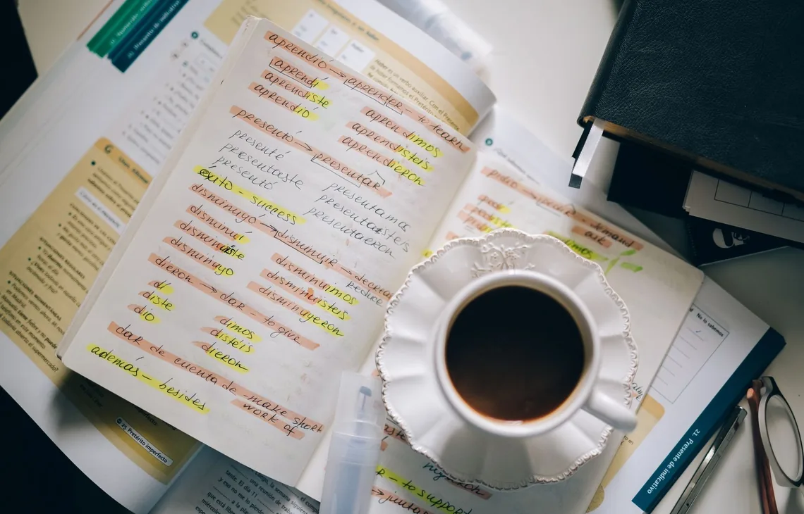 A cup of coffee on handwritten Spanish notes for language learning inspiration.
