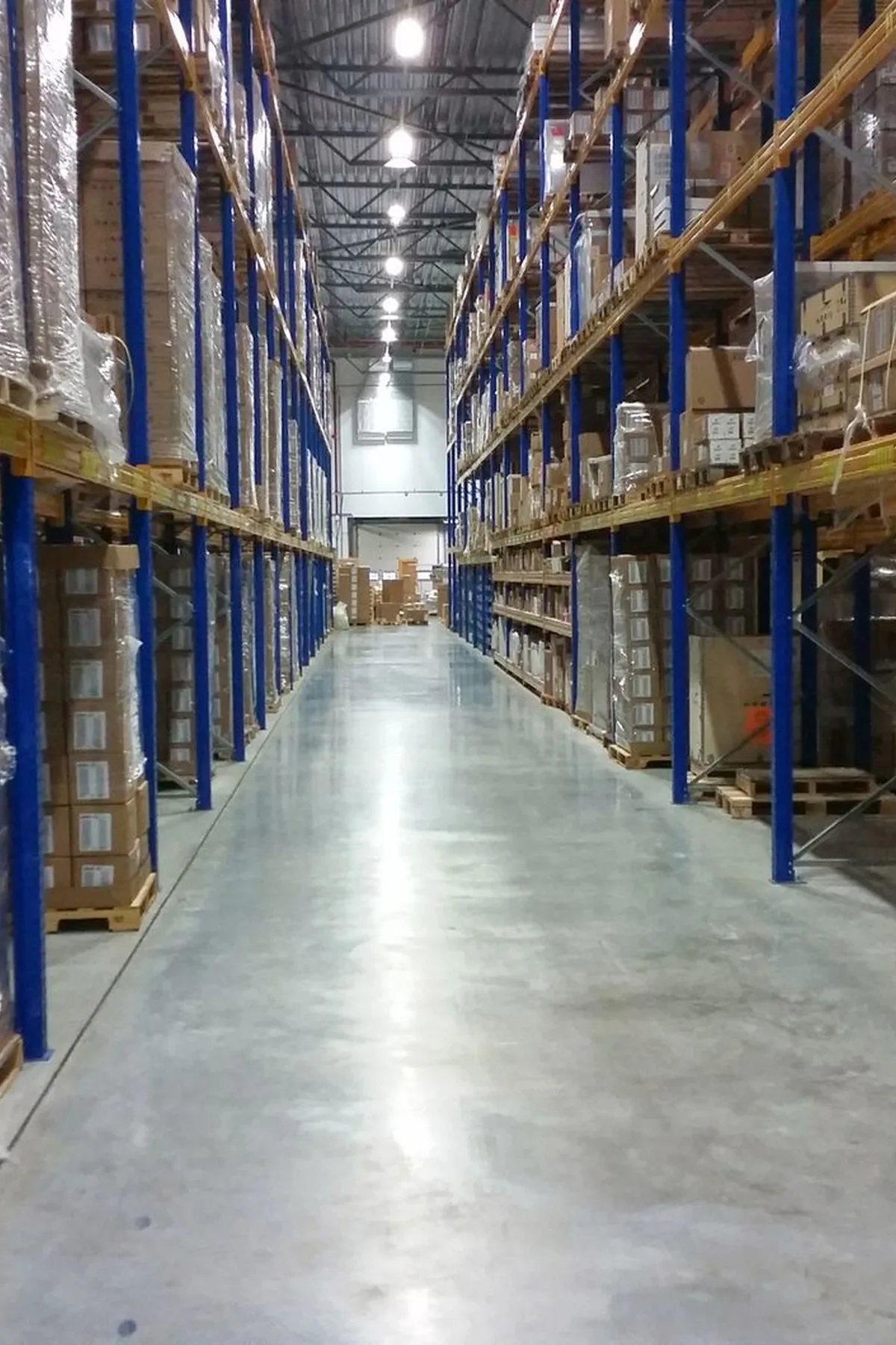 Interior view of a large warehouse aisle lined with stacks of organized cardboard boxes.