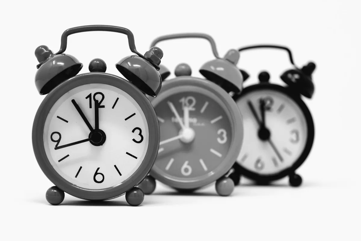 Monochrome image of three vintage alarm clocks highlighting the passage of time.