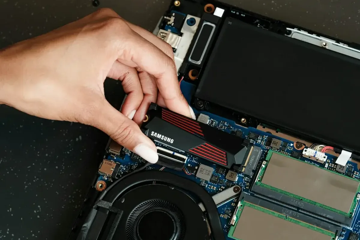 Dłoń montująca dysk SSD Samsung z radiatorem do laptopa obok pamięci RAM