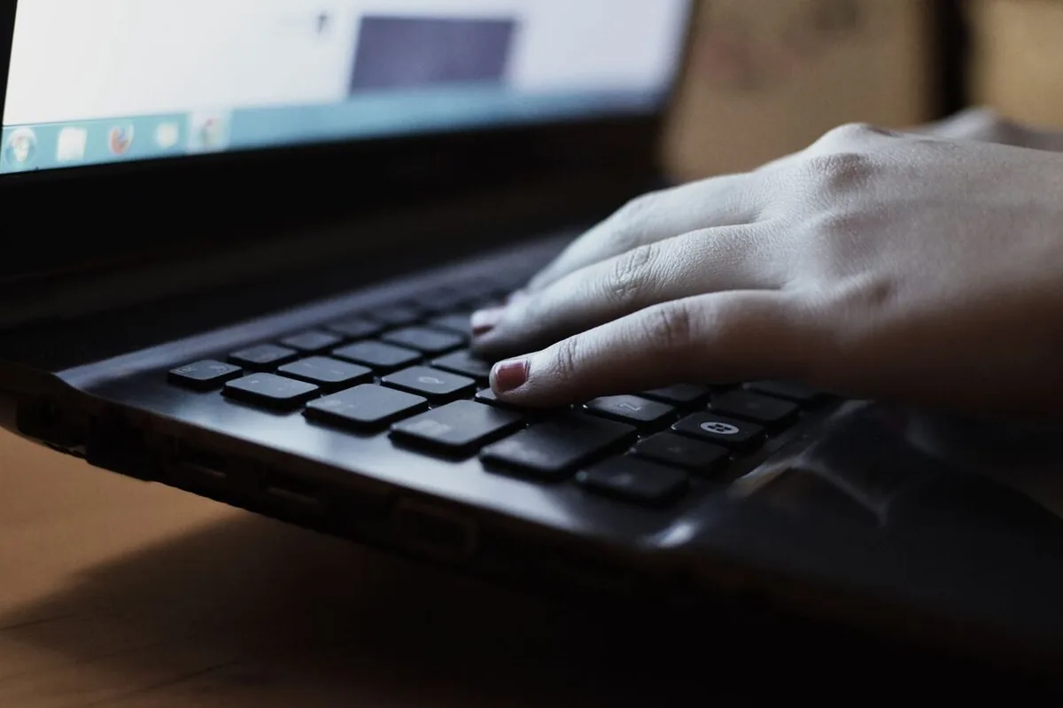 dłoń wpisująca tekst na klawiaturze laptopa