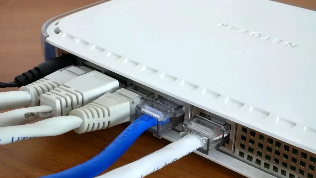 Router Netgear z podłączonymi kablami sieciowymi na drewnianym blacie