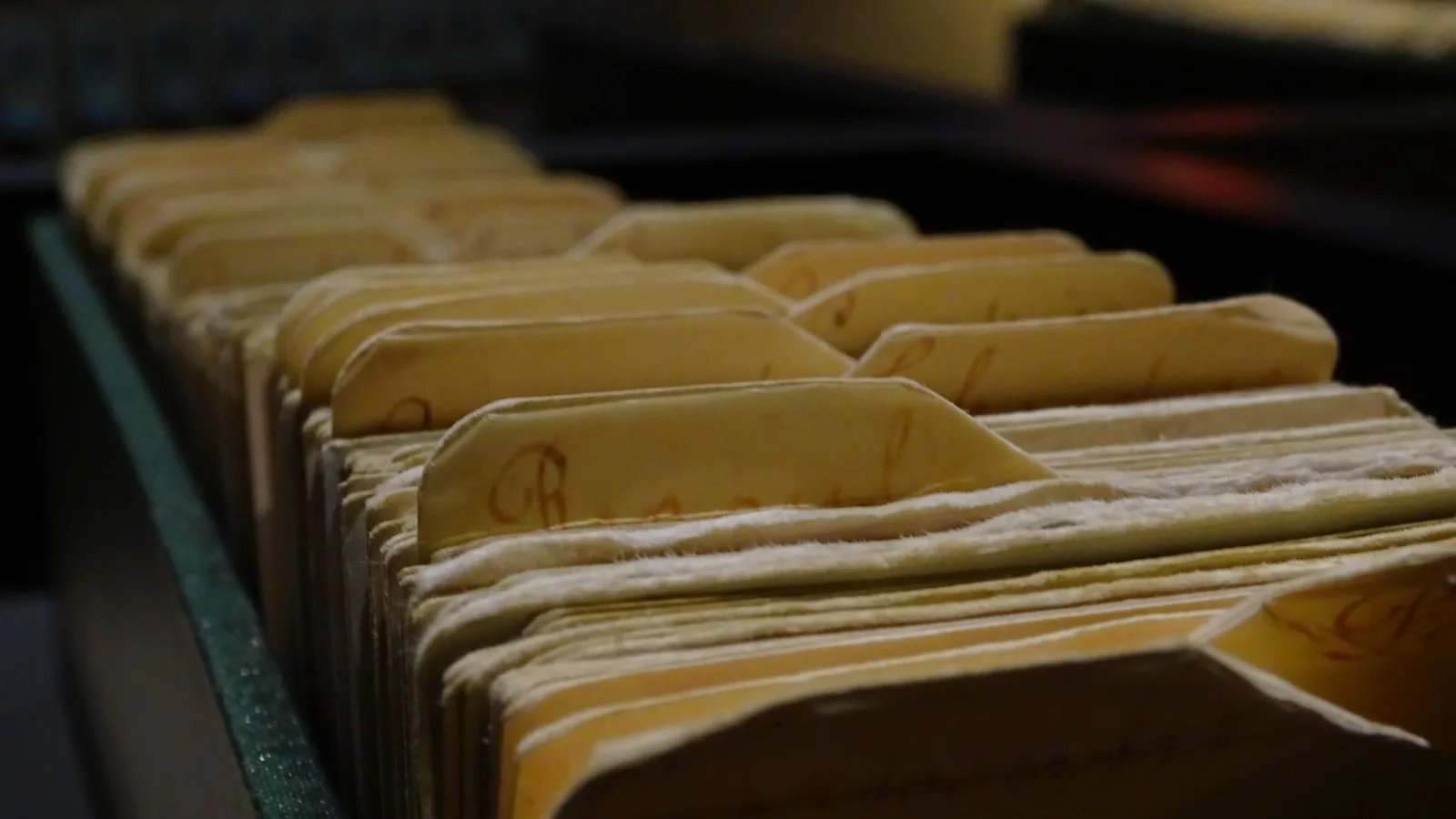 Vintage file folders organized in a row inside a dimly lit room.