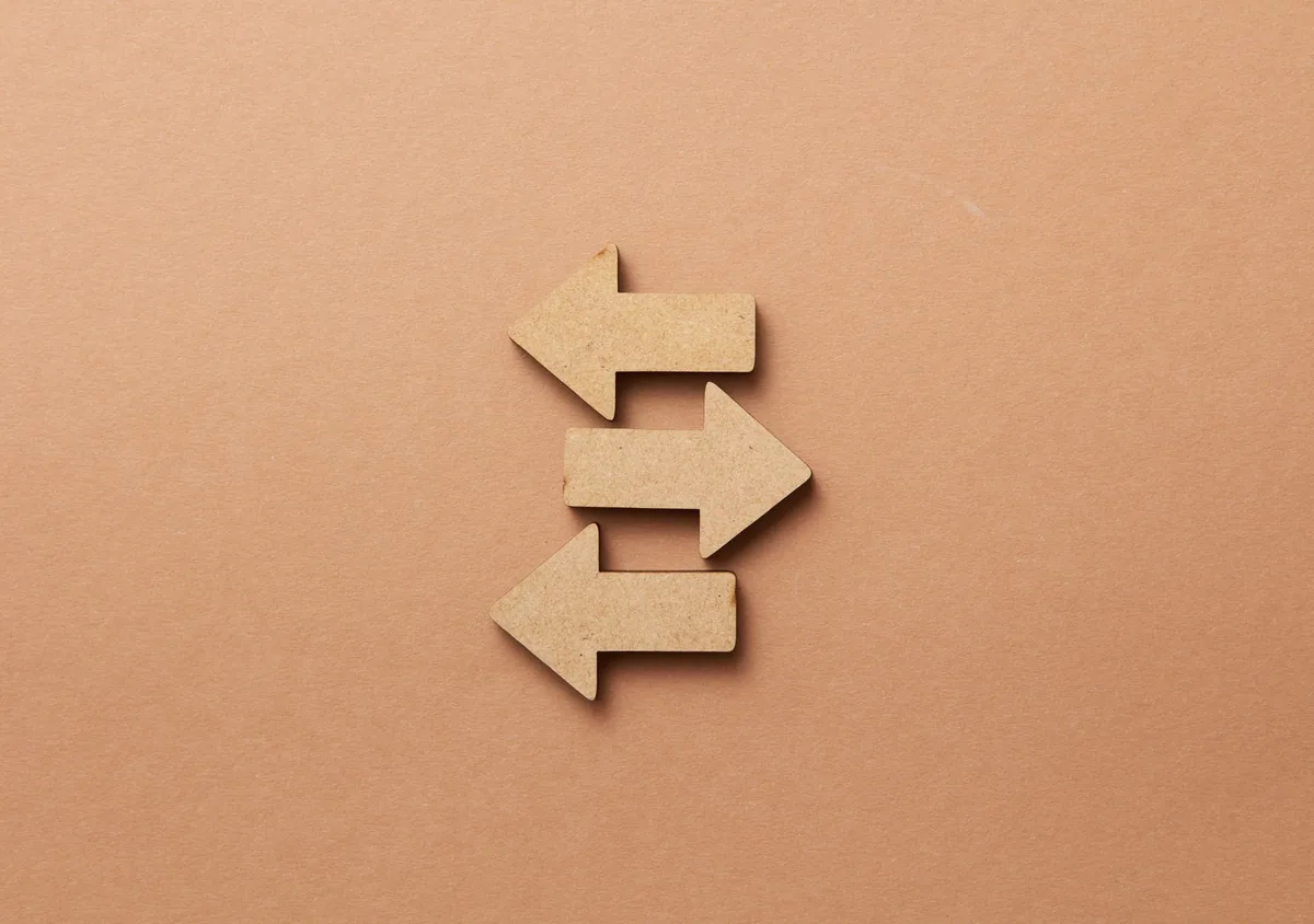 Close-up of three wooden arrows pointing in opposite directions on a beige surface.
