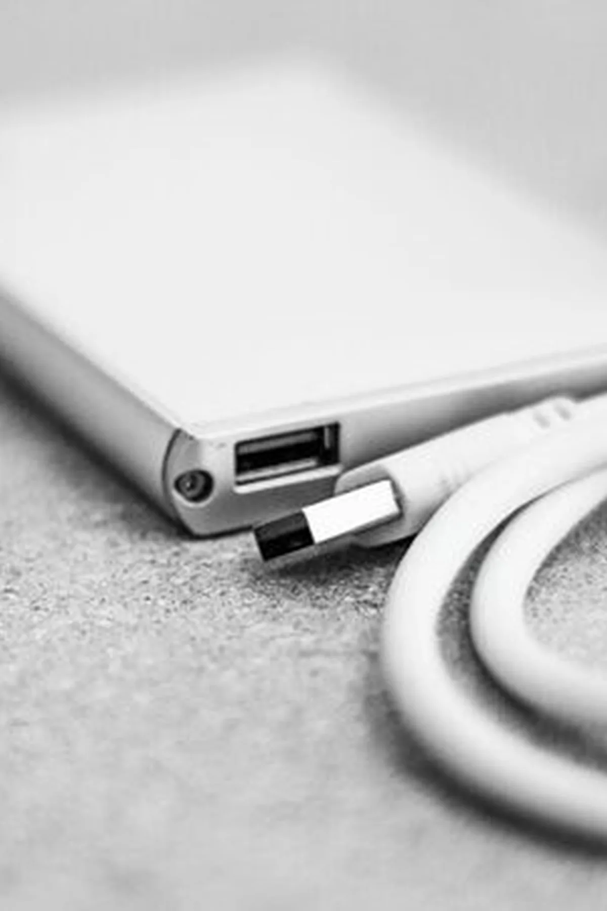 Czarno-białe zdjęcie zewnętrznego dysku z podłączonym kablem USB