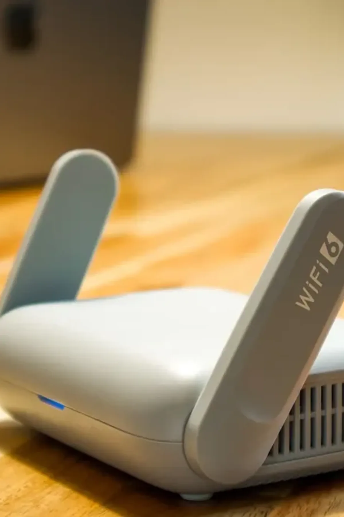 Router z anteną i oznaczeniem WiFi 6 stojący na drewnianym blacie