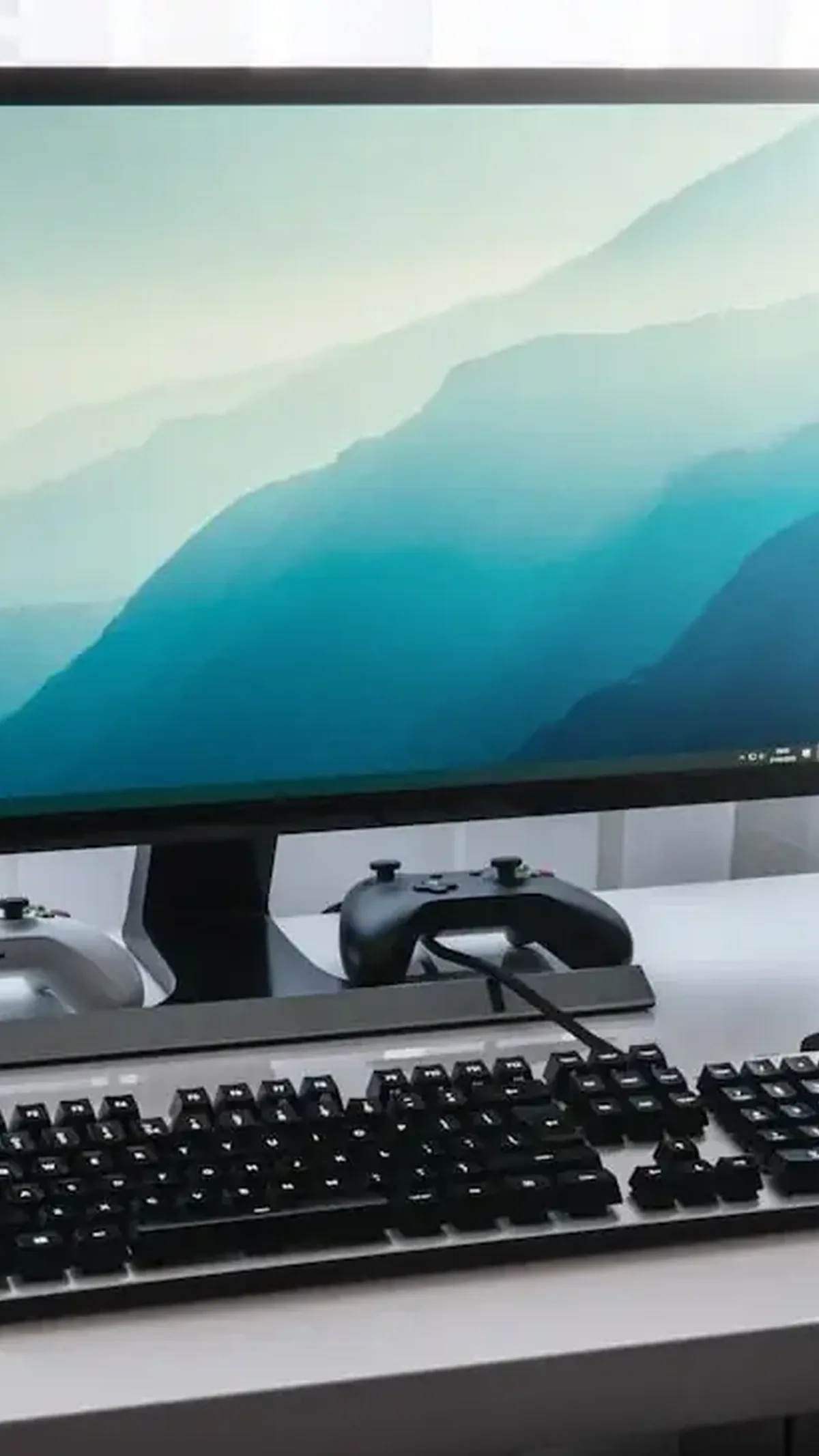 Zestaw komputerowy z monitorem, klawiaturą mechaniczną i padami do gier na białym biurku