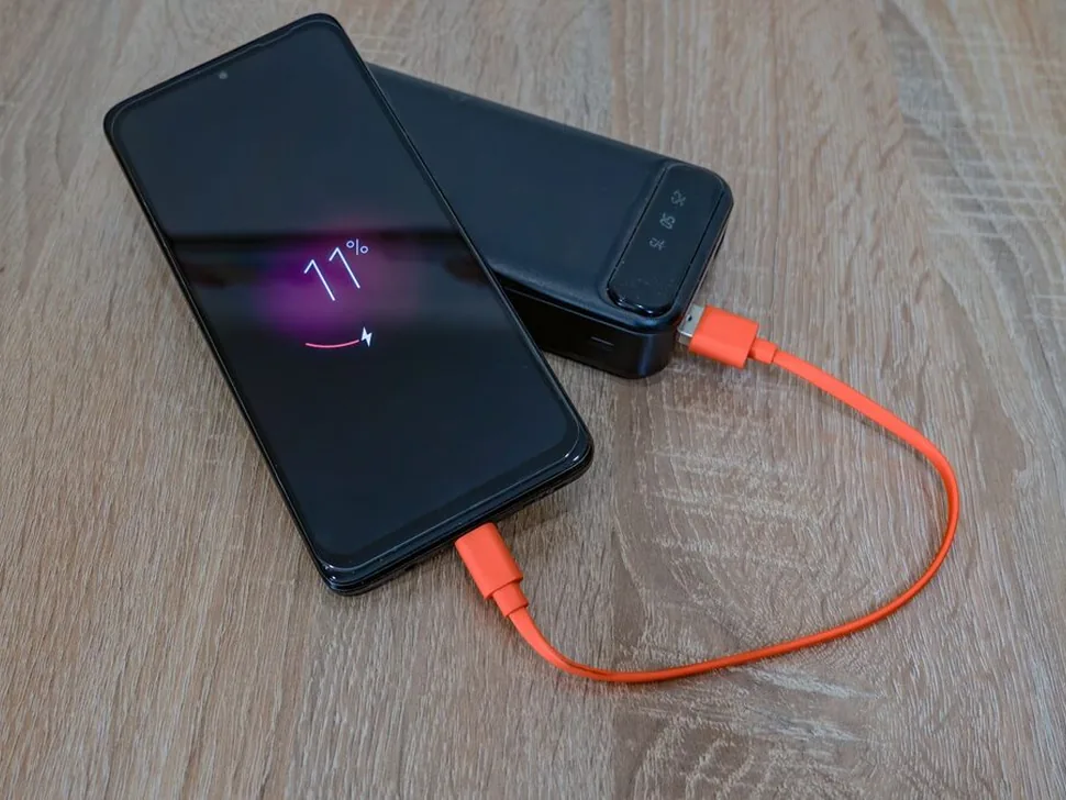 Smartfon z widocznym poziomem baterii 11% ładowany od powerbanku