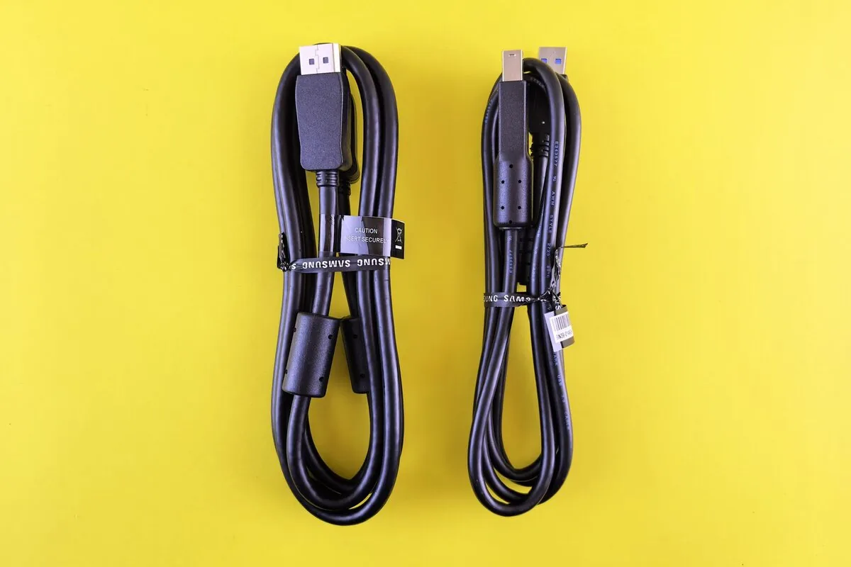 Dwa zwinięte czarne kable USB spięte opaskami na żółtym tle