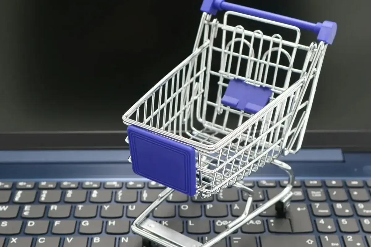 miniaturowy wózek sklepowy stojący na klawiaturze laptopa