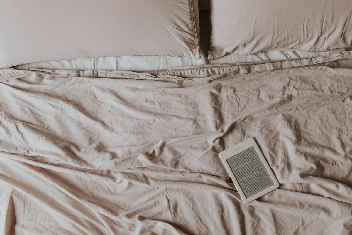 czytnik Kindle na łóżku z beżową pościelą — Amazon Kindle Oasis 2 a zakres naszego serwisu — czym zajmujemy się zamiast