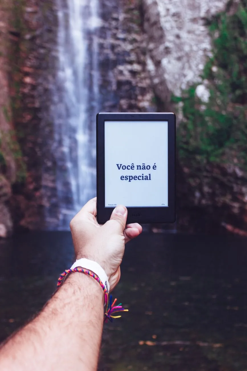 dłoń trzymająca czytnik e-booków na tle wodospadu — Amazon Kindle Paperwhite 5 a zakres naszego serwisu — czym zajmujemy się zamiast