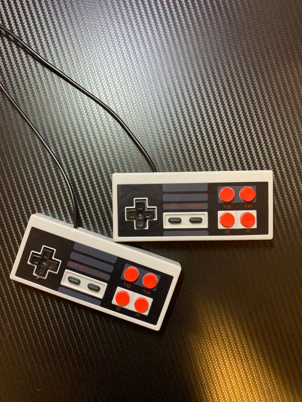 dwa przewodowe kontrolery retro na powierzchni z włókna węglowego — Amiga 500 Mini — czego przy tym sprzęcie nie zrobimy