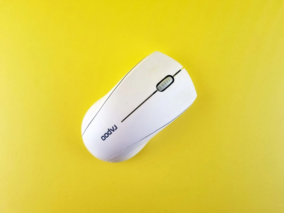 minimalistyczna biała mysz bezprzewodowa na żółtym tle — Corsair Scimitar RGB a zakres naszego serwisu — czym zajmujemy się zamiast