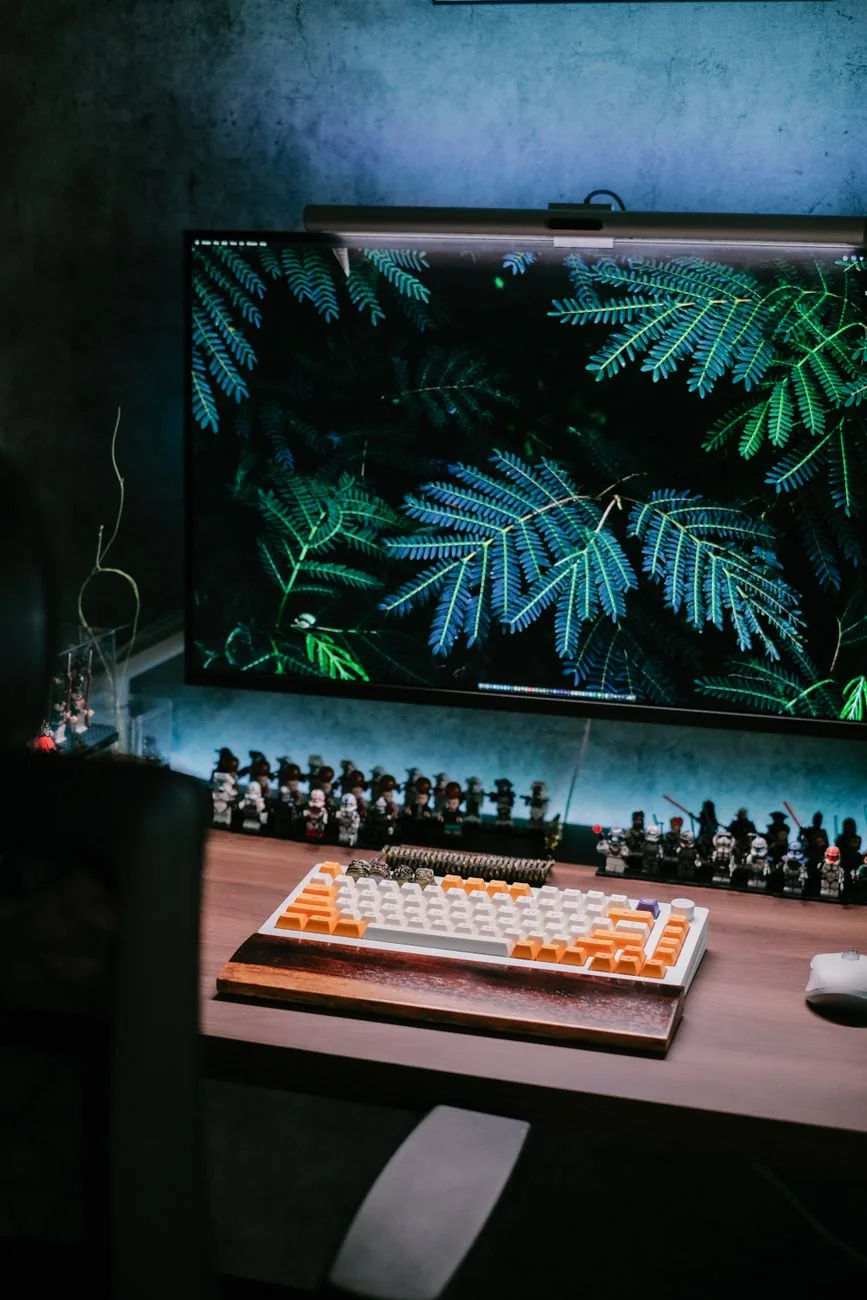 duży monitor z grafiką liści i klawiatura mechaniczna na biurku — Dell Alienware AW3225QF poza naszym warsztatem — gdzie szukać pomocy