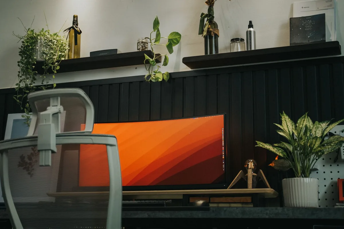 zakrzywiony monitor na biurku z fotelem ergonomicznym i roślinami — Dell P2222H a zakres naszego serwisu — czym zajmujemy się zamiast