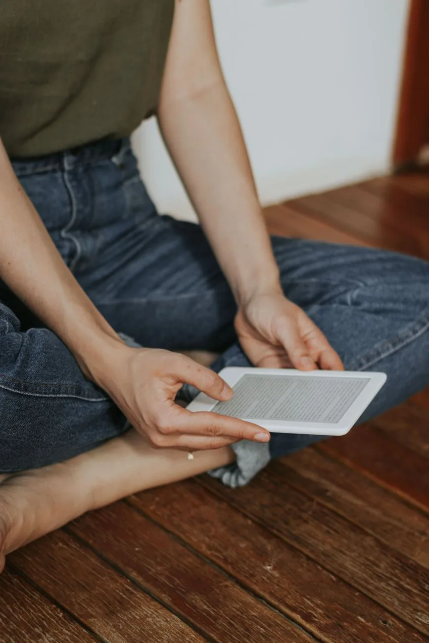 czytnik e-booków trzymany na drewnianej podłodze — Dlaczego nie bierzemy Amazon Kindle Colorsoft do naprawy