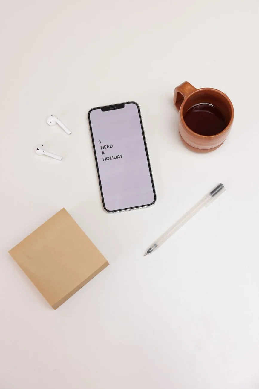 telefon komórkowy ze słuchawkami dousznymi i kawą na białym biurku — Dlaczego nie bierzemy ASUS Zenfone 9 do naprawy