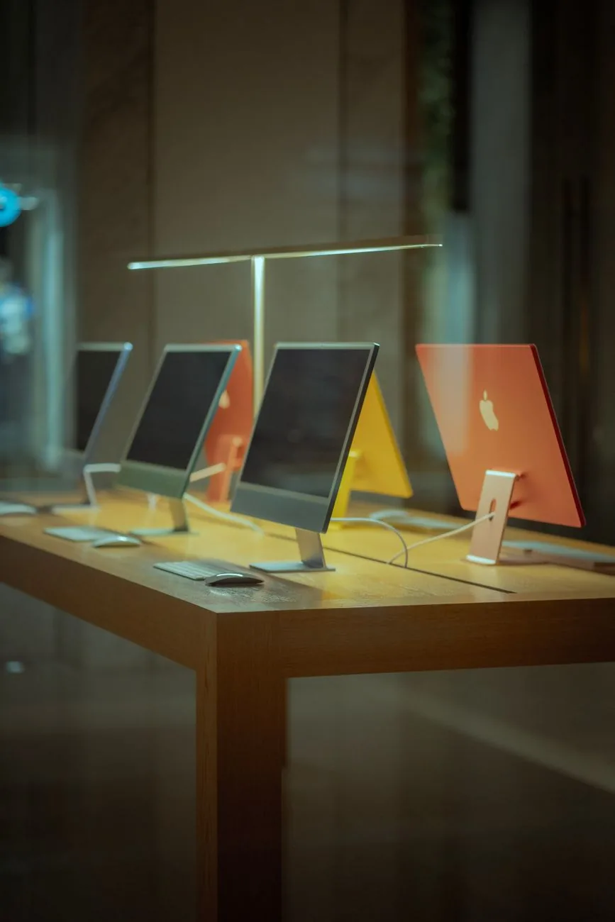 kolorowe komputery stacjonarne na drewnianym stole — Dlaczego nie bierzemy iMac 21,5 cala (2011) do naprawy