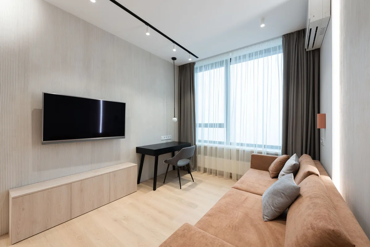 telewizor na ścianie w salonie z sofą i zasłonami — Dlaczego nie bierzemy LG OLED evo G3 do naprawy