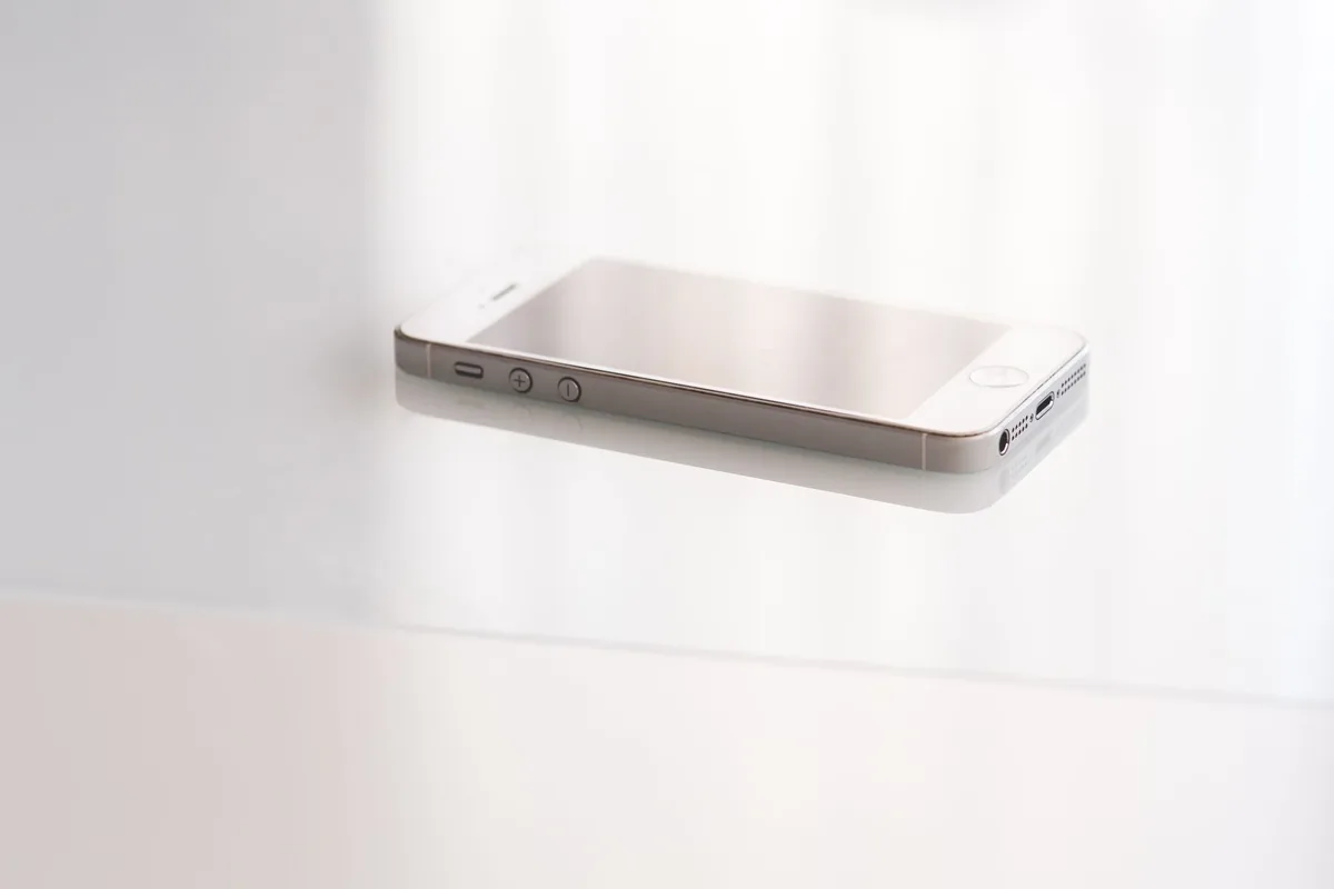 biały elegancki smartfon na lśniącej powierzchni odbijającej — Dlaczego nie bierzemy Motorola Moto E13 do naprawy