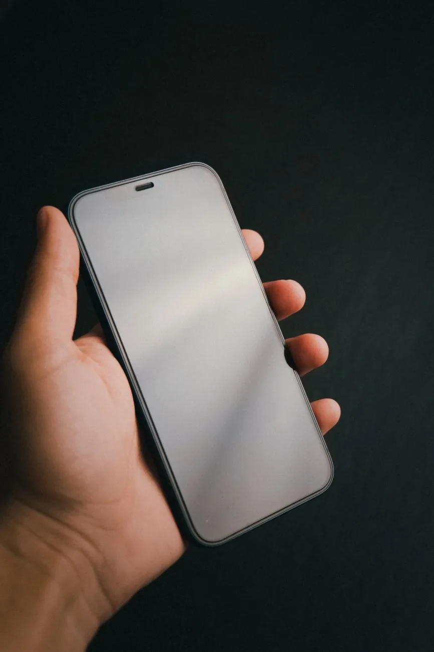 dłoń trzymająca smartfon na ciemnym tle — Dlaczego nie bierzemy Motorola Moto G31 do naprawy