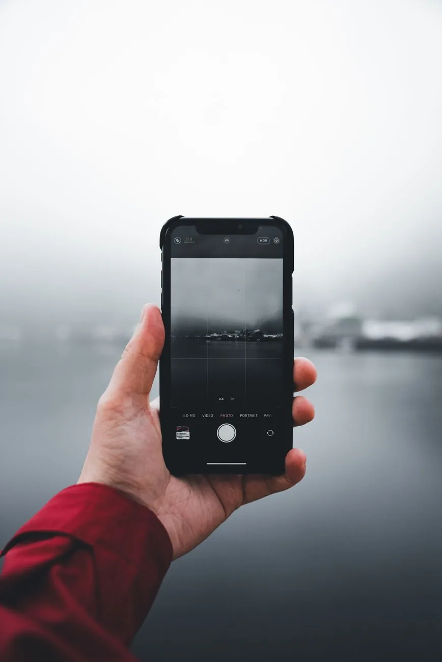 telefon komórkowy skierowany na mglisty krajobraz — Dlaczego nie bierzemy Nothing Phone 2 do naprawy