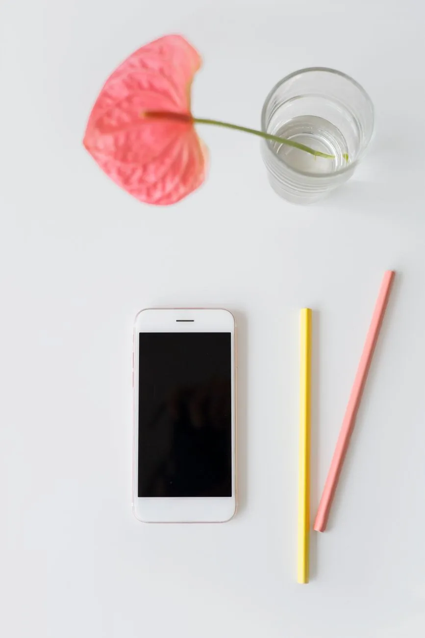 smartfon obok kolorowych kredek i wazonu z kwiatem na białym tle — Dlaczego nie bierzemy OnePlus Nord do naprawy
